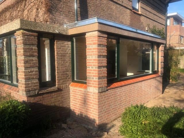 Brick extension with corner windows, dark frames and a stone and orange tile sill