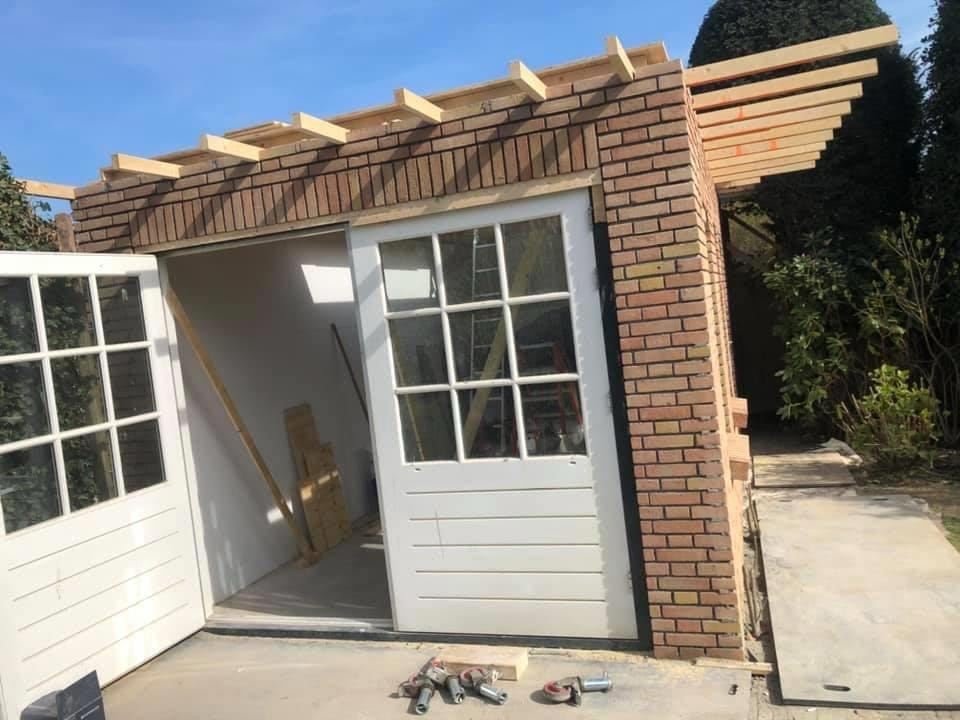 Brick garden building under construction with timber roof joists and white double doors