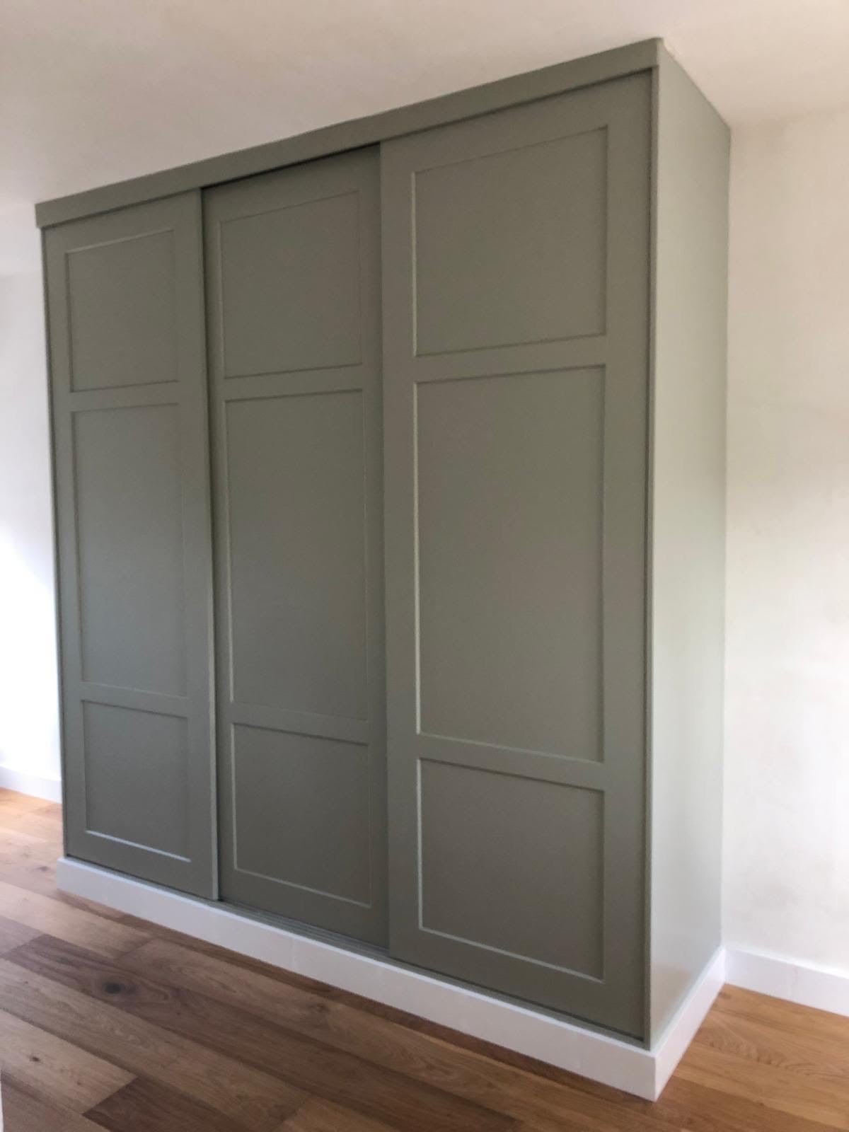Fitted wardrobe with three green panelled sliding doors