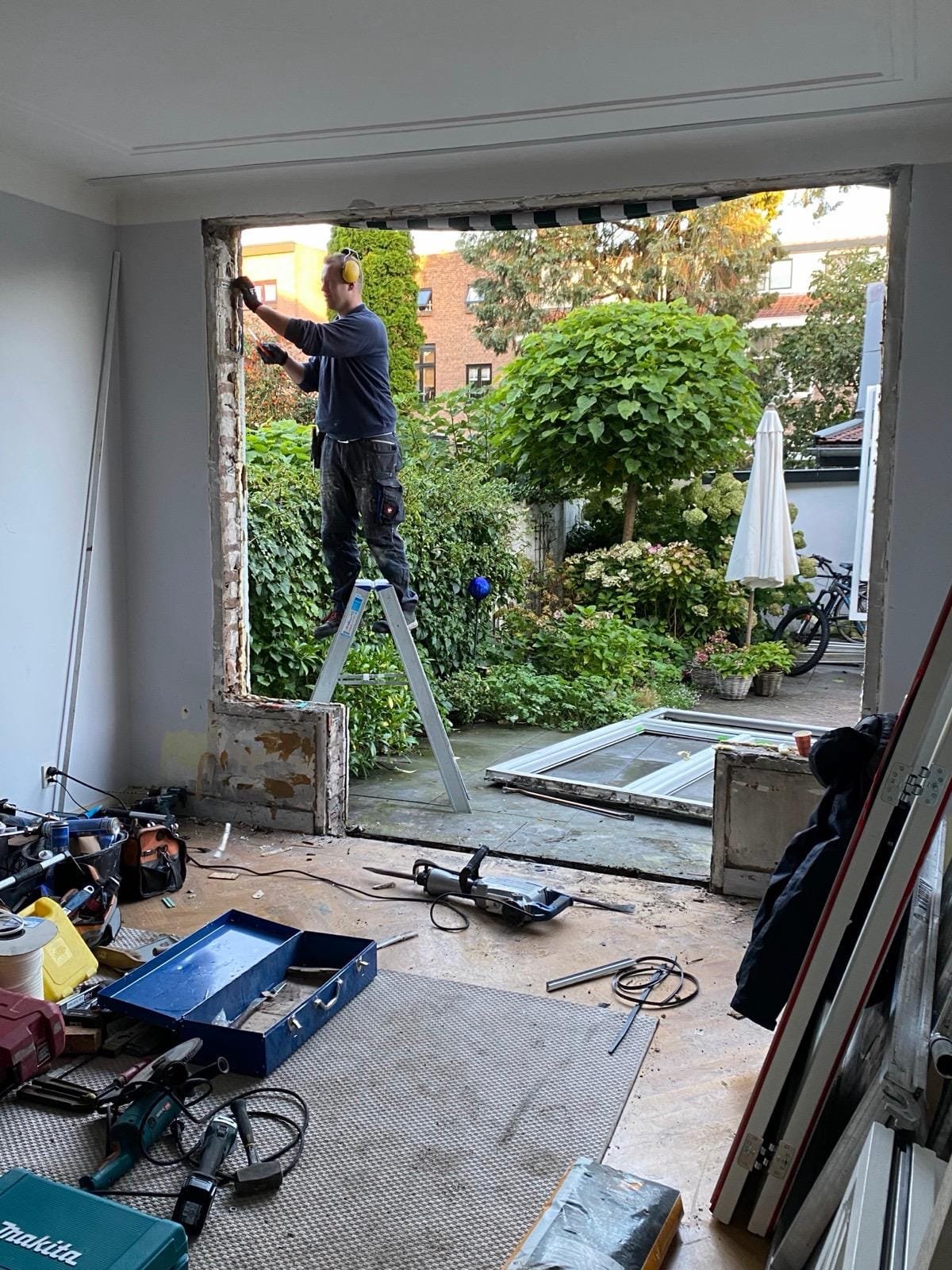 Carpenter on a ladder fitting a new frame in a wide wall opening