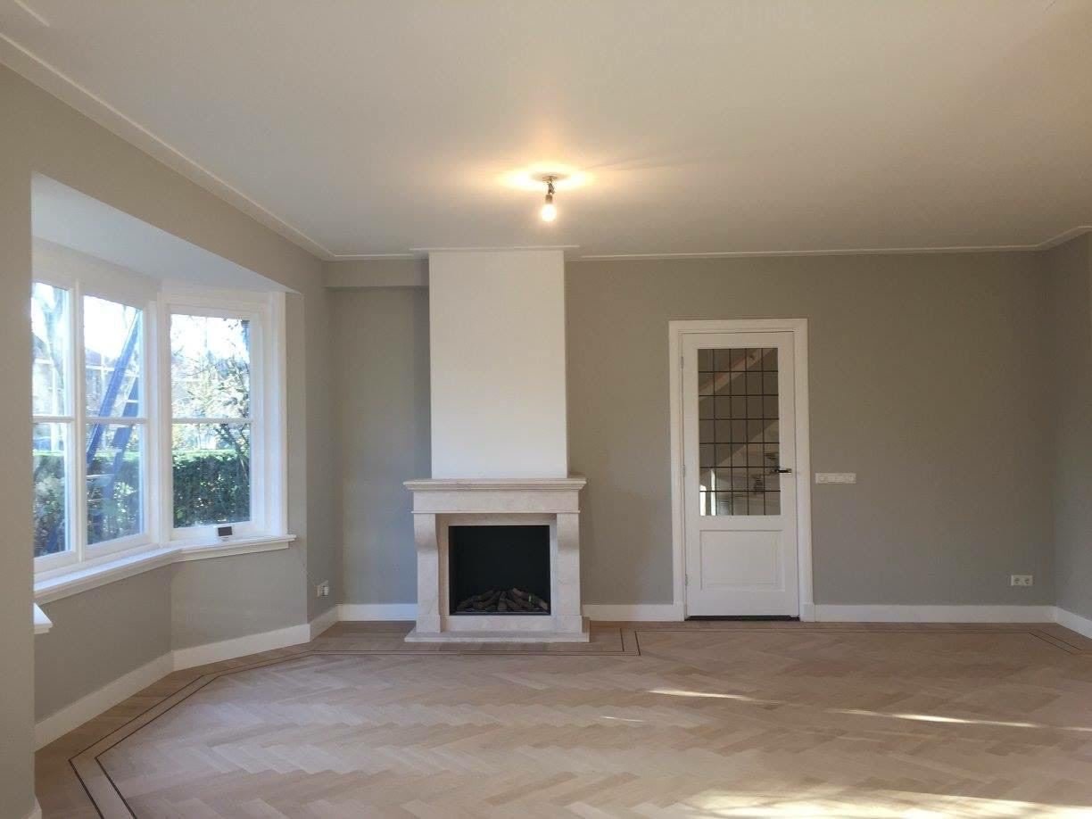 Freshly painted living room with bay window, white fireplace and a new herringbone floor