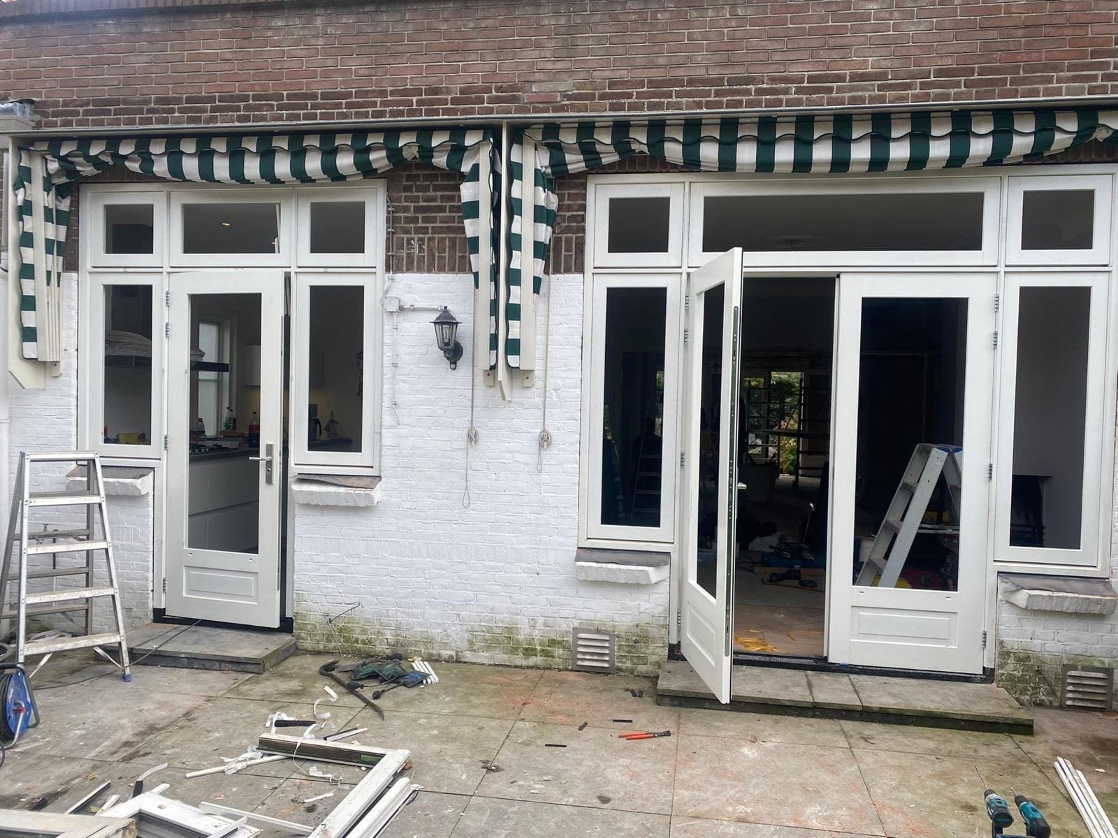 Rear facade with new white timber frames, transom windows and double garden doors under striped awnings