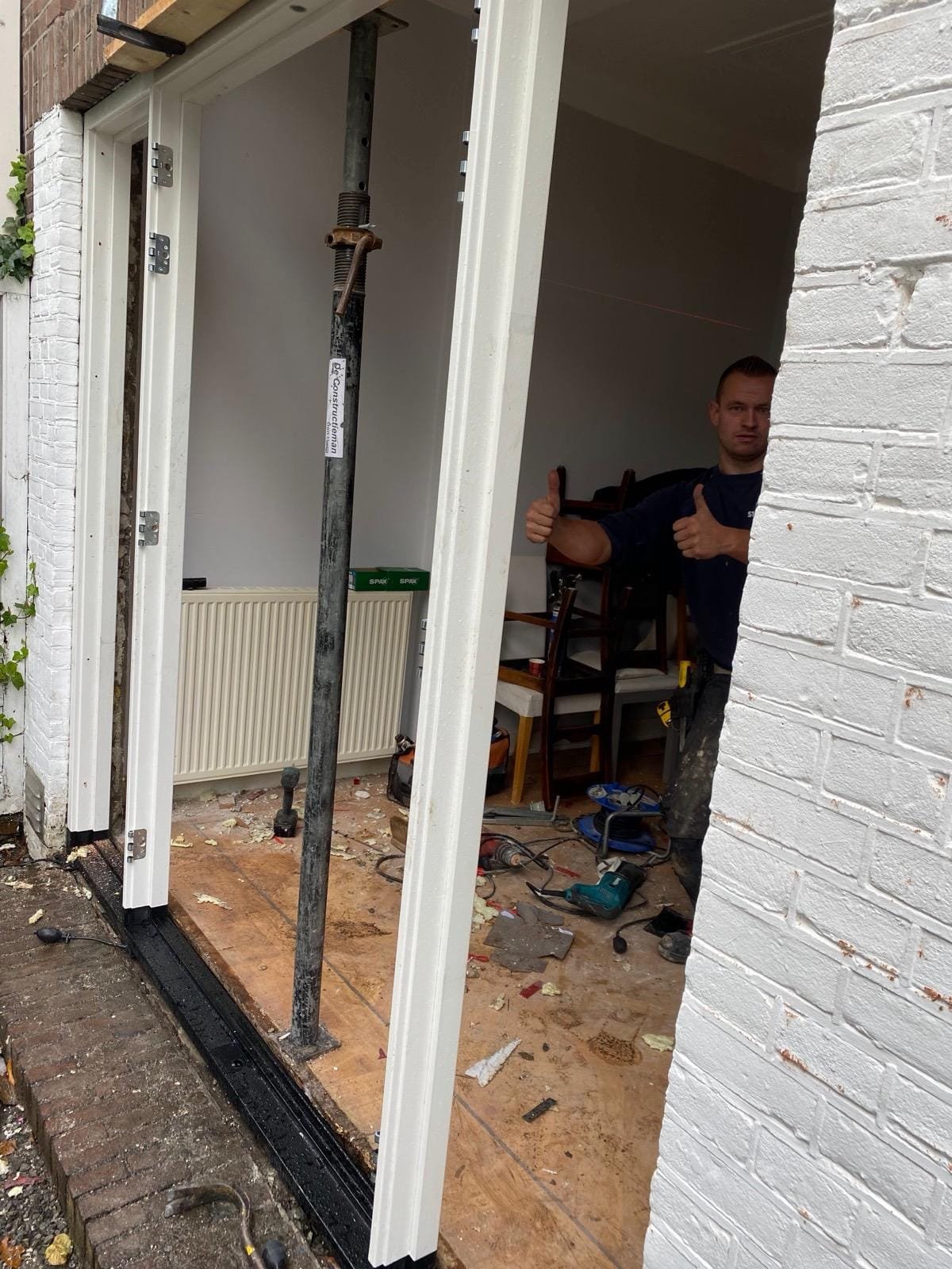 Temporary steel prop in a wall opening next to new white garden doors