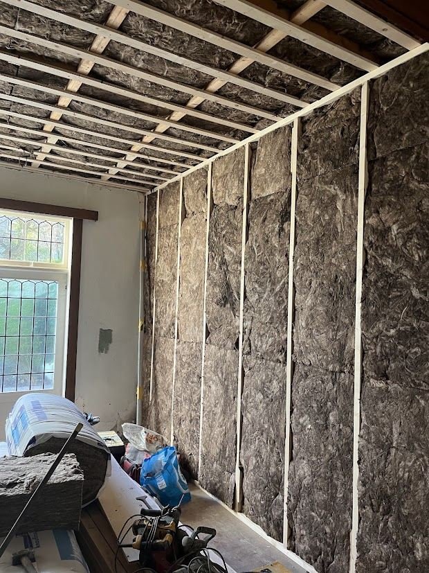 Room in an older home with walls and ceiling insulated with mineral wool between timber battens